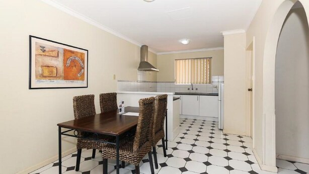 Cocina compacta con comedor, piso de baldosas, estufa y ventana con persianas.