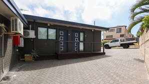 Un edificio con fachada oscura, números en las puertas y entrada pavimentada.