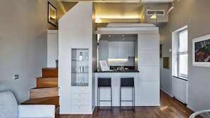 A compact kitchen with a built-in bar, a dining area with two stools, and a staircase leading to an upper level. - Attico Vista Mare sul Porticciolo di Camogli by Wonderful Italy (Camogli)