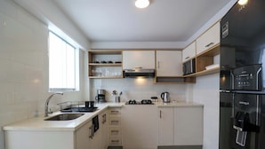 Una cocina moderna con armarios blancos, un refrigerador de acero inoxidable y un horno empotrado.