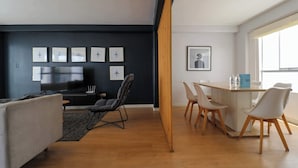 Una sala moderna con un sofá, un televisor y una zona de comedor con sillas y una mesa.