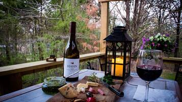 A wooden table with a bottle of wine, a glass of red wine, cheese, and olives.