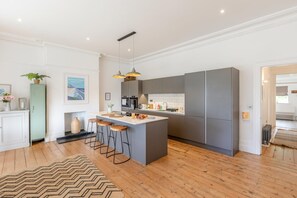 A modern kitchen with a central island, bar stools, and a herringbone-patterned rug. - 3 Bed in Mortehoe (oc-pines) (Mortehoe)