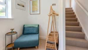 A room with a bed, a small table with a vase, a framed picture, a ladder with baskets, and a staircase. - 3 Bed in Mortehoe (oc-pines) (Mortehoe)