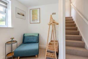 Une pièce comprenant un lit, une petite table avec un vase, un tableau encadré, une échelle avec des paniers et un escalier.