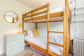 Ein Schlafzimmer mit Etagenbetten, einem Schminktisch, einem Spiegel, einer Lampe und einer Heizung.