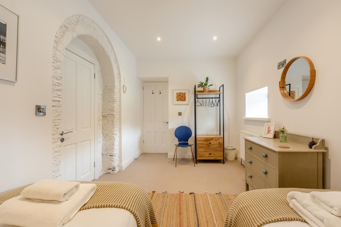 Une chambre à coucher avec un lit, une chaise, une commode, un miroir et une porte.