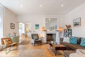 A spacious living room with a fireplace, a sofa, a chair, and a dining area.