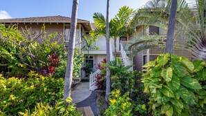 Un edificio de varios pisos con una galería techada rodeada de exuberante vegetación tropical.