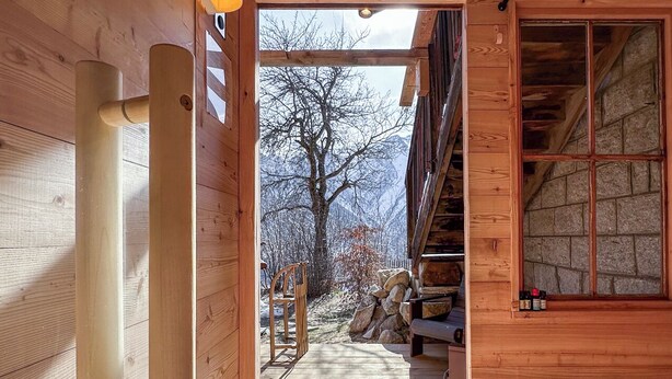 A wooden interior with a wooden staircase leading to a balcony, a metal bucket, and a wooden door. - Hideaway Chalet Faazihaus in Ruhiger Panoramalage (Martisberg)