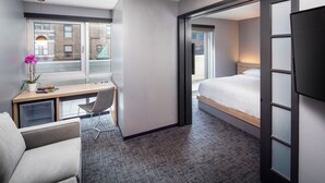 Une chambre d’hôtel avec un lit, un bureau, une chaise et une vue sur l’extérieur.