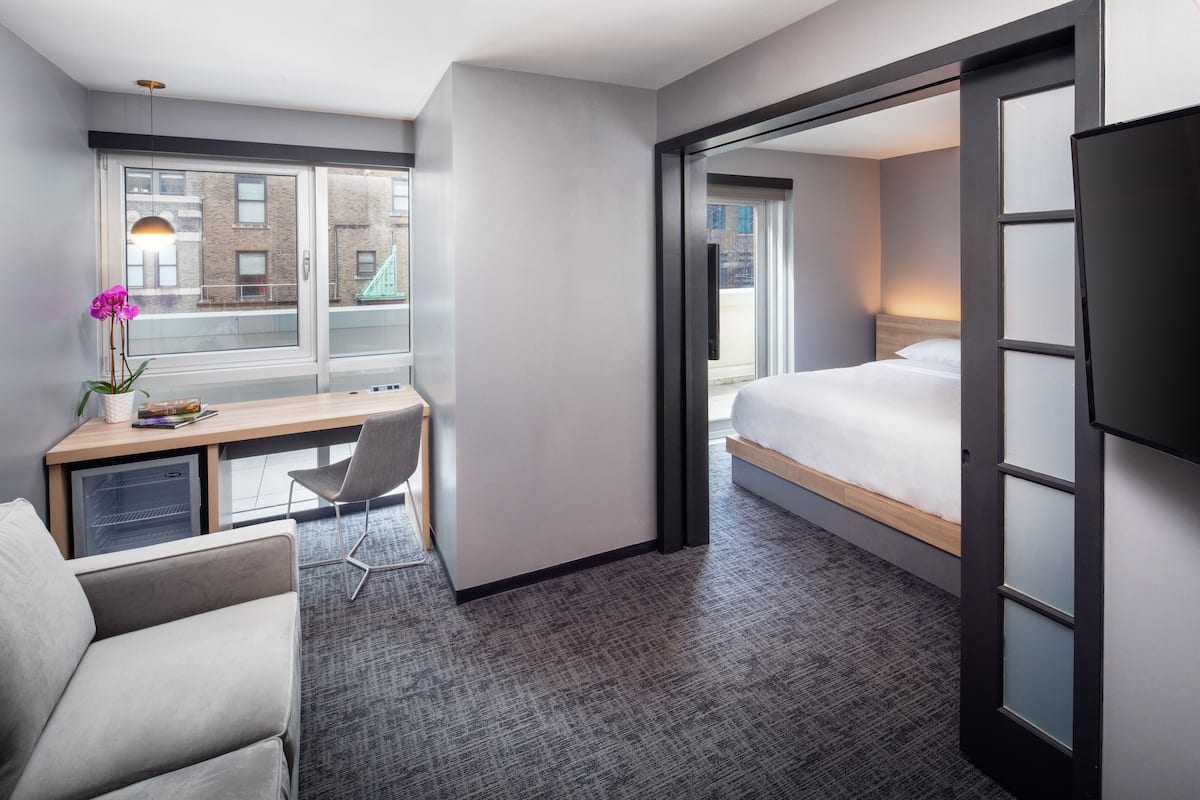 Une chambre d’hôtel avec un lit, un bureau, une chaise et une vue sur l’extérieur.