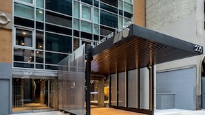 L’entrée d’un hôtel au design moderne, avec des portes en verre et une allée couverte.