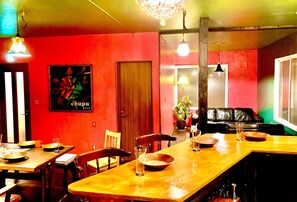 A dining area with wooden tables and chairs, a red wall, and a poster. - chupubase Mon Furanos Last Paradise Rokugo abo / Furano Hokkaidō (Furano)