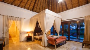 Un dormitorio con cama con dosel, mesita de noche, lámpara y vistas al exterior.