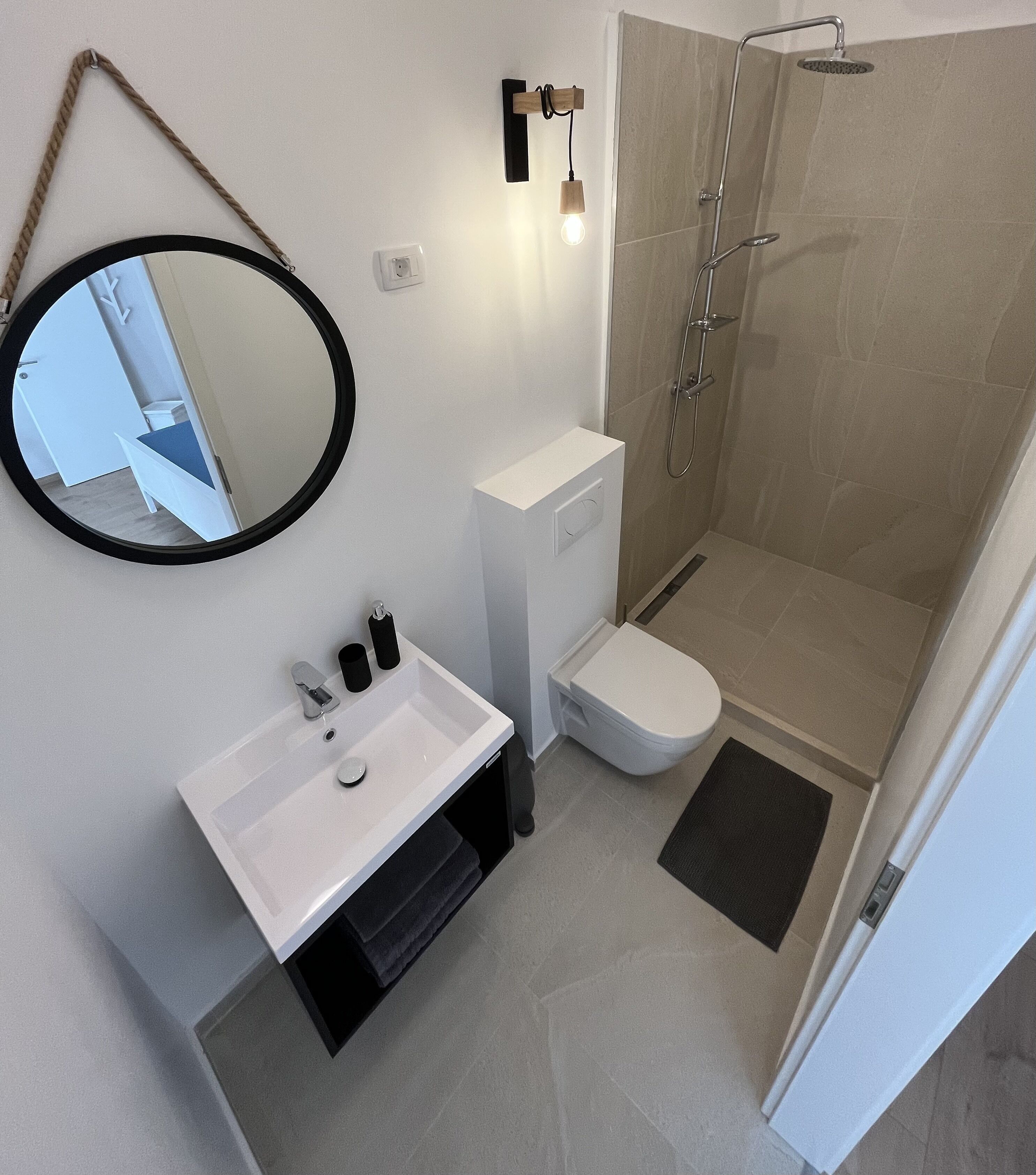 Ein modernes Badezimmer mit Waschbecken, Toilette und Dusche – alles in Weiß.