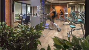 Un gimnasio con equipo de ejercicio, vigas de madera y un pilar de piedra.