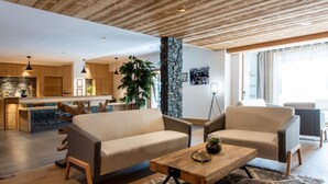 Una sala de estar moderna con un sofá, sillas, una mesa de centro y un pilar de piedra.