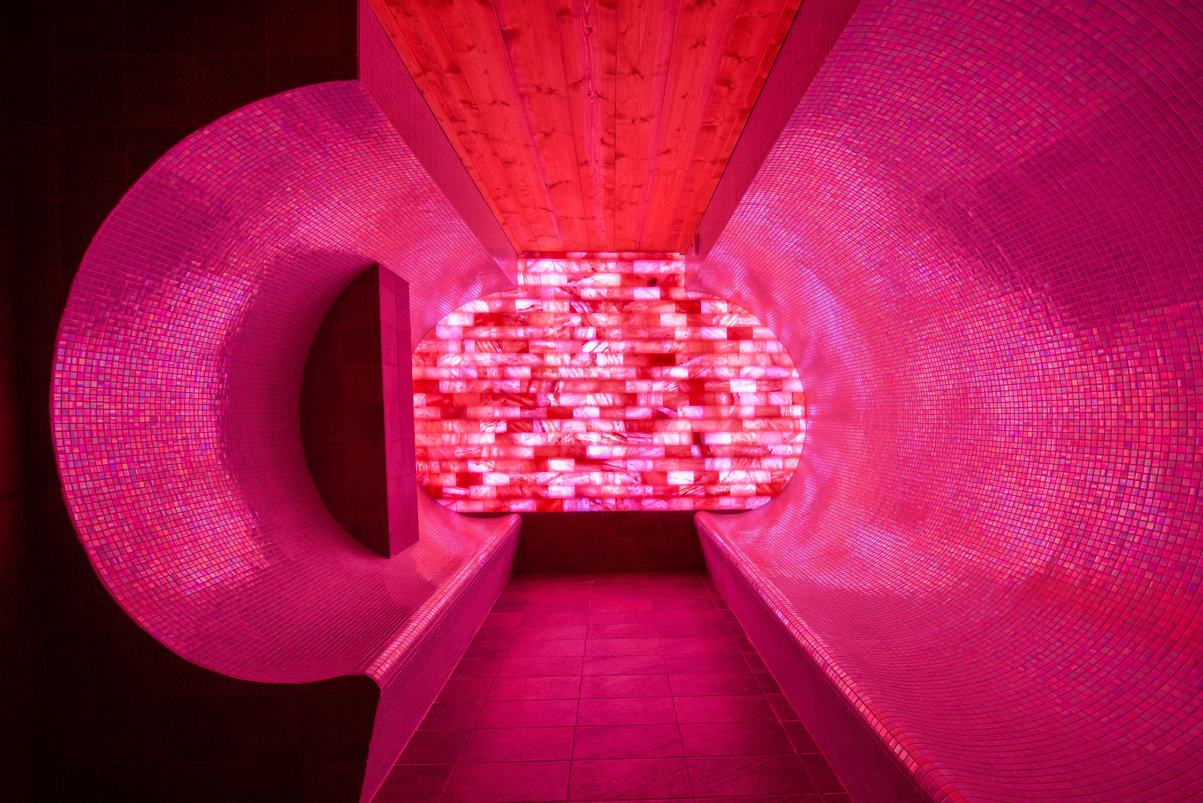 A tunnel-like structure with a grid pattern on the walls and ceiling, illuminated by red lighting.