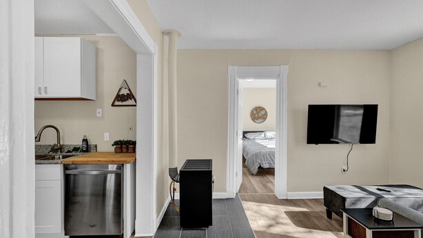 Ett kompakt bostadsutrymme med ett litet pentry, en säng, en TV och en liten sittgrupp.