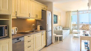 A modern kitchen with wooden cabinets, stainless steel appliances, and a dining area with a view. - Kallisti (Mykonos)