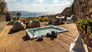 A wooden deck with a hot tub, lounge chairs, and a view of the sea. - Kallisti (Mykonos)