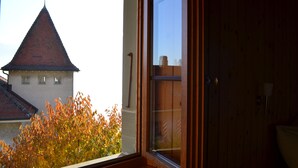 Une vue depuis une fenêtre, avec une porte en bois, donnant sur un bâtiment dont le toit est rouge.