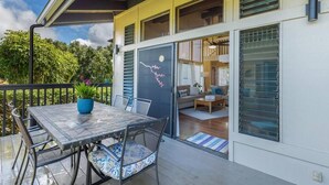 Ein modernes Haus mit einer Terrassenfläche, die einen Tisch, Stühle, einen Blumentopf und einen Blick ins Innere durch eine Glastür bietet.
