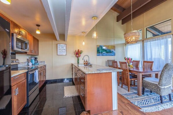 A modern kitchen with wooden cabinets, a central island, and a dining area with a table and chairs.