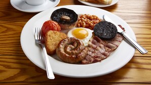 A breakfast plate with eggs, bacon, sausages, tomatoes, beans, and toast on a wooden table. - The Boat & Horses Inn (Oldham)