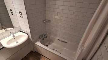 A bathroom with a sink, bathtub, and tiled walls.
