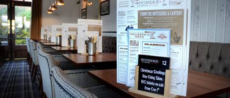 A restaurant interior with a menu board, seating area, and pendant lighting.
