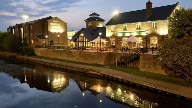 A riverside hotel with a traditional brick facade, a tower, and outdoor seating areas. - The Boat & Horses Inn (Oldham)