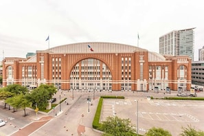 A large, red-brick building with a prominent arched entrance and multiple flags. - Cozy Stay minutes from The Star! W/Pool & Gym - Near Top Golf and PGA Frisco! (The Colony)