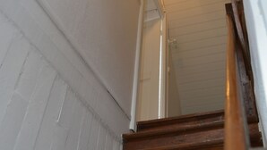 Una escalera de madera con paredes blancas y un accesorio de iluminación en la parte superior.
