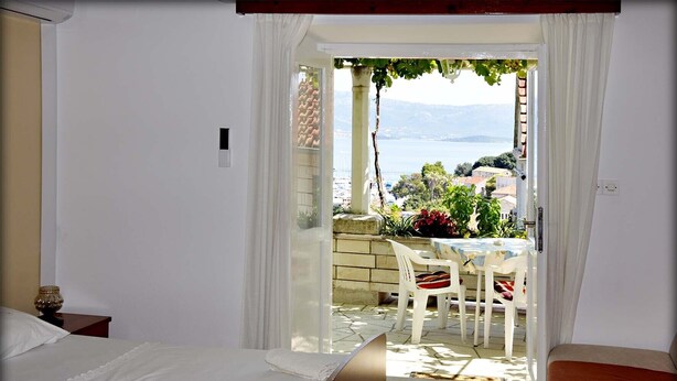 Une chambre à coucher avec un lit, une table de chevet et une vue sur un balcon équipé d’une table et de chaises.