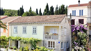 Un bâtiment traditionnel avec un toit en tuiles, un balcon orné de fleurs et une façade en pierre.