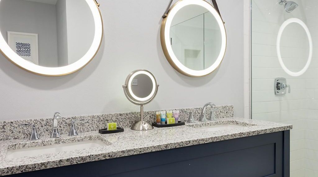 A bathroom with a granite countertop, three sinks, and three mirrors.