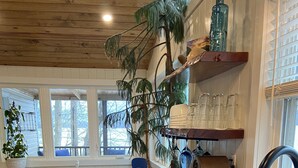 Une cuisine avec des plans de travail en bois, un évier, un coin repas avec une chaise bleue et une plante en pot.