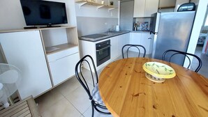 Cozinha compacta com TV, mesa de jantar e cadeiras.