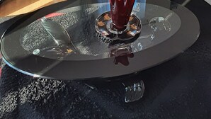 Un salon moderne avec un ensemble de canapés, une table basse agrémentée d’un objet décoratif et une vue sur l’extérieur à travers une fenêtre avec des rideaux.