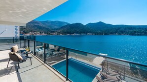 Un balcon avec piscine, donnant sur un lac et des montagnes.