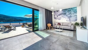 Un salon moderne doté d’une grande porte-fenêtre coulissante donnant sur un balcon aménagé avec du mobilier d’extérieur.