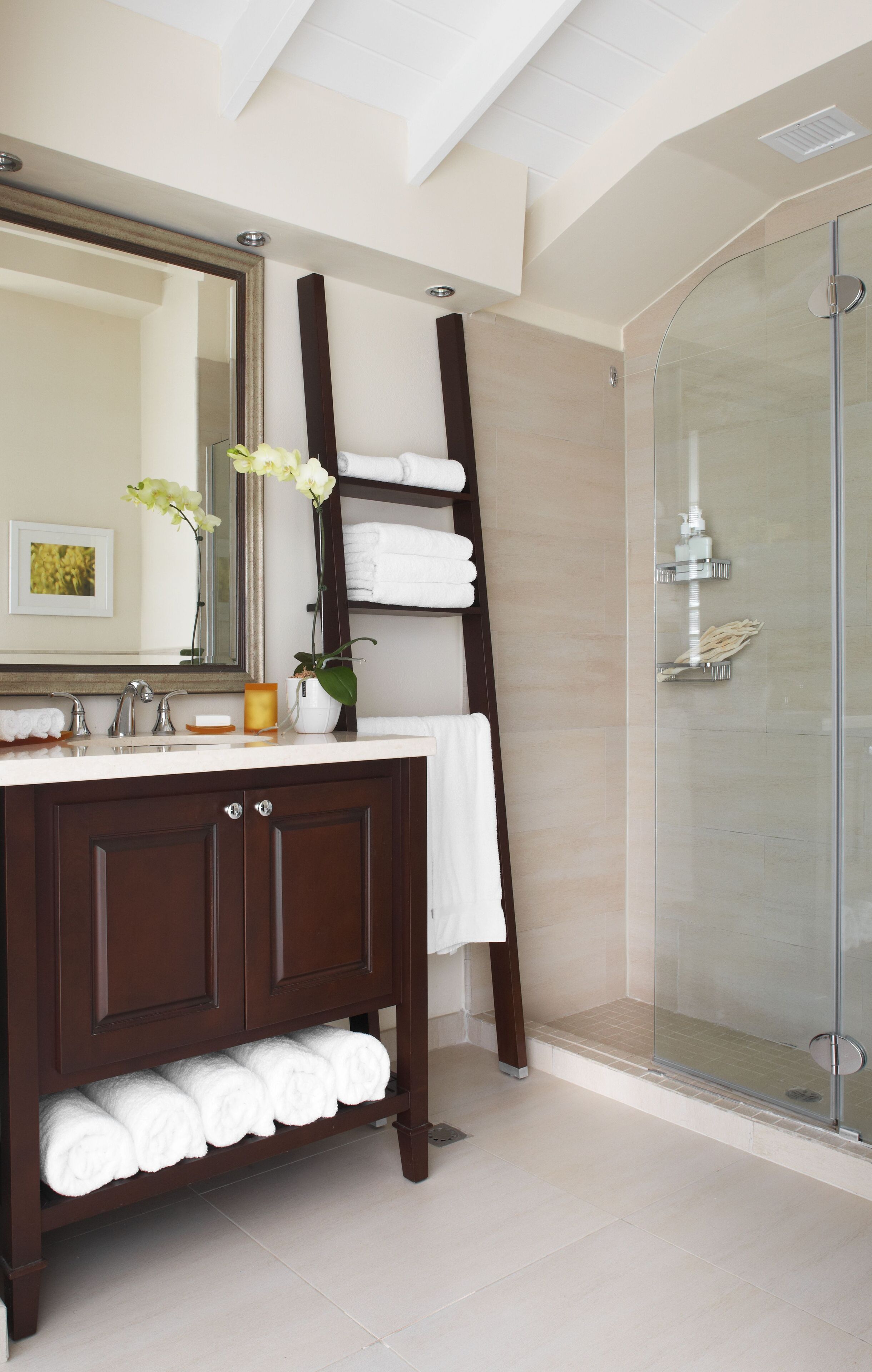A modern bathroom with a glass shower enclosure, a wooden vanity with a mirror, and neatly folded towels.