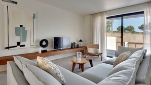 Una sala de estar moderna con un sofá grande, un televisor y vistas al exterior.