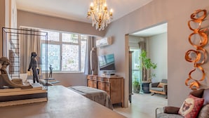 Een ruime woonkamer met een grote bank, een houten kast, een televisie en een kroonluchter.