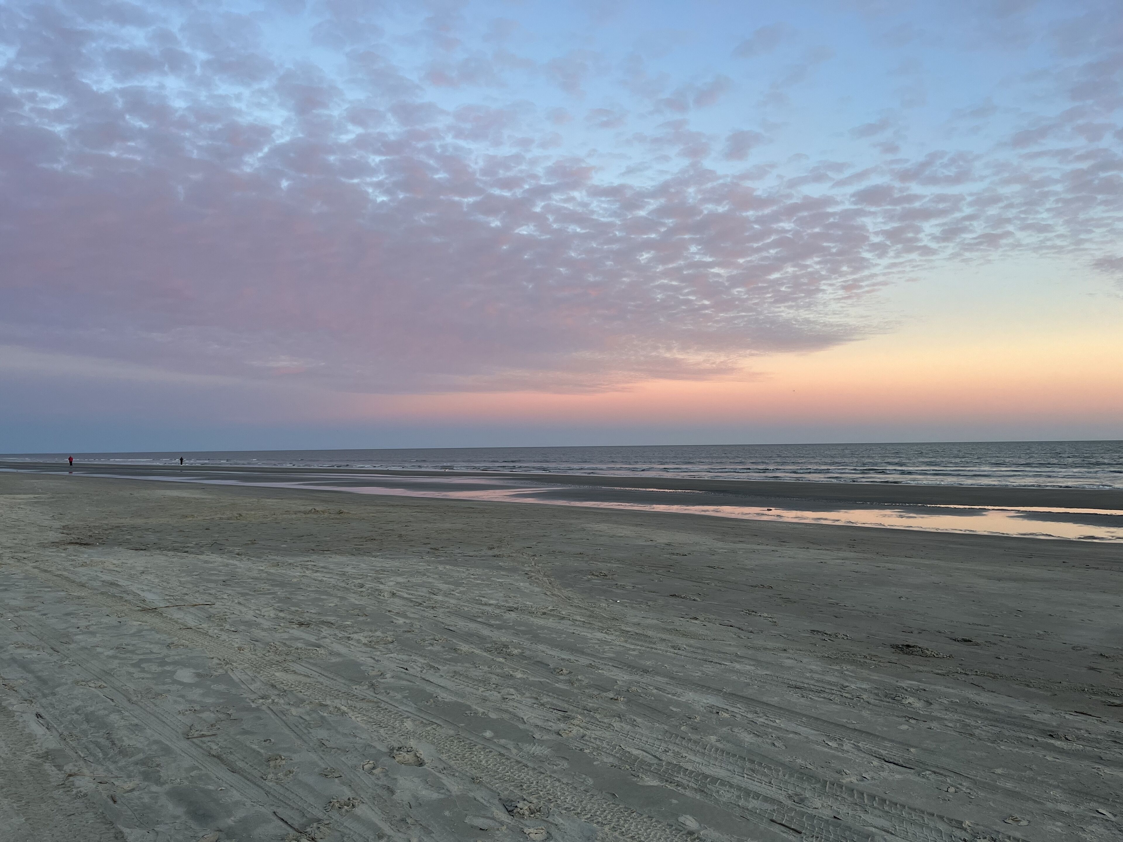 Ein Strand mit einer weiten Sandfläche und ruhigem Meer.