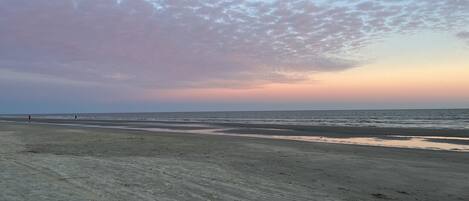 Ein Strand mit einer weiten Sandfläche und ruhigem Meer.
