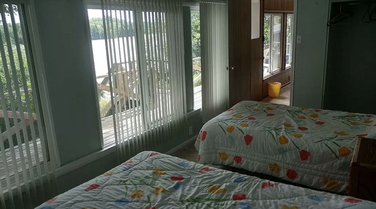 Un dormitorio con dos camas, un balcón y vistas al exterior.