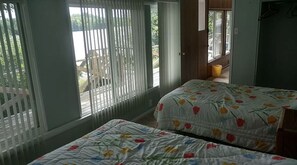 A bedroom with two beds, a balcony, and a view of the outdoors.
